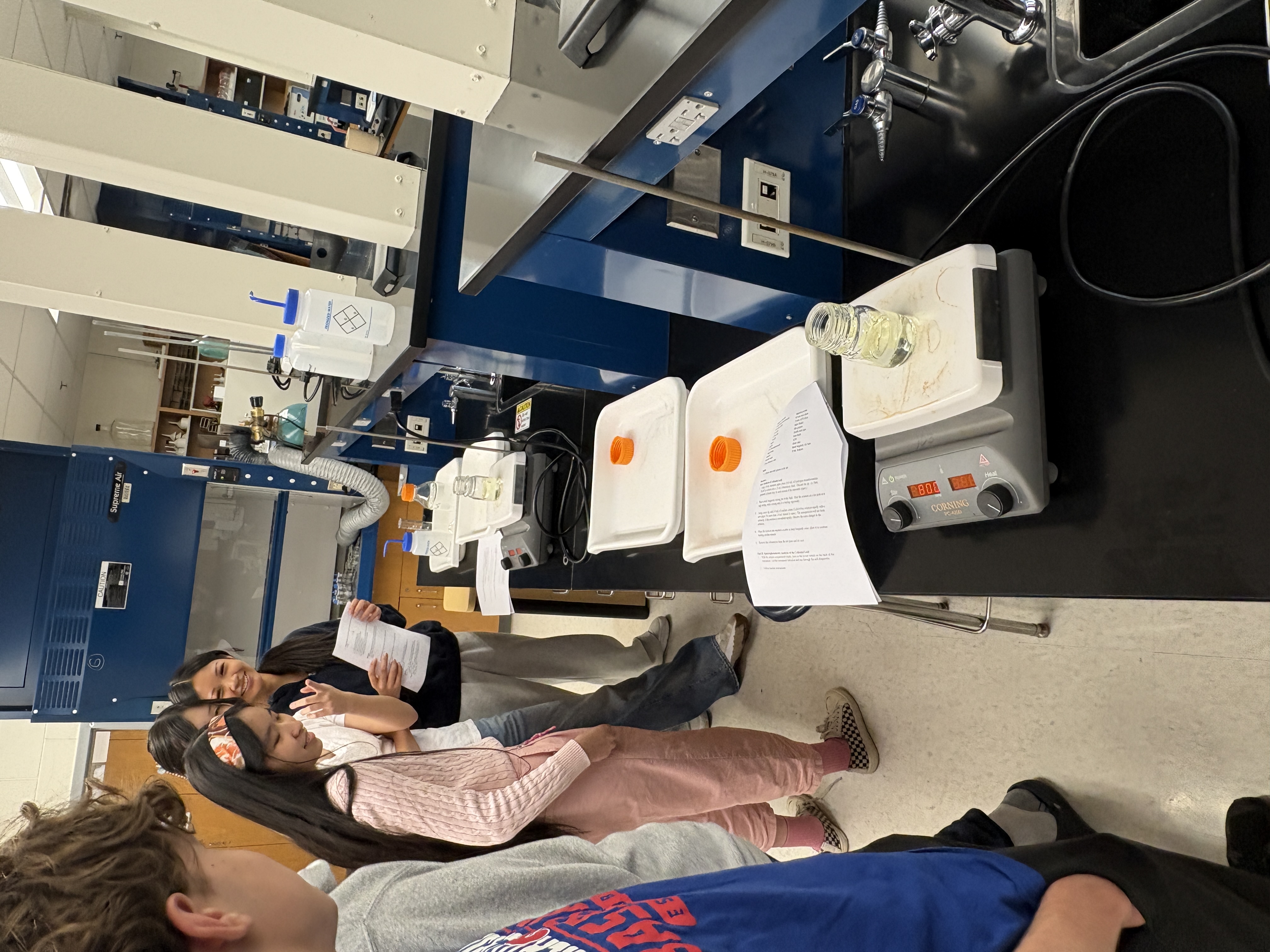 Officers and members gathered around a lab bench